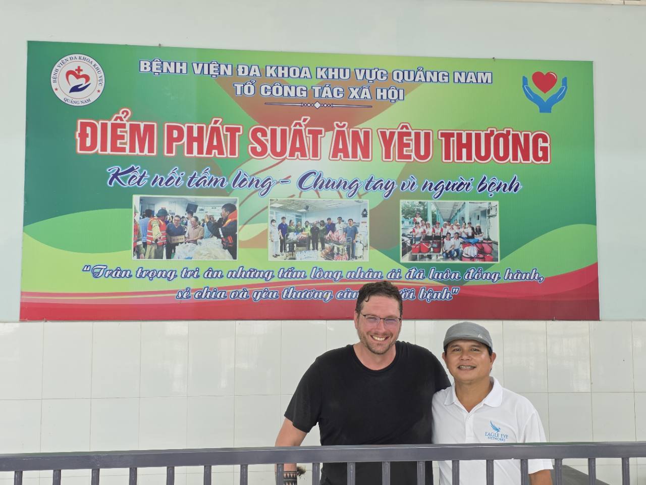 Jerry and Vuong standing together beneath the hospital’s Social Work Team meal-distribution sign.