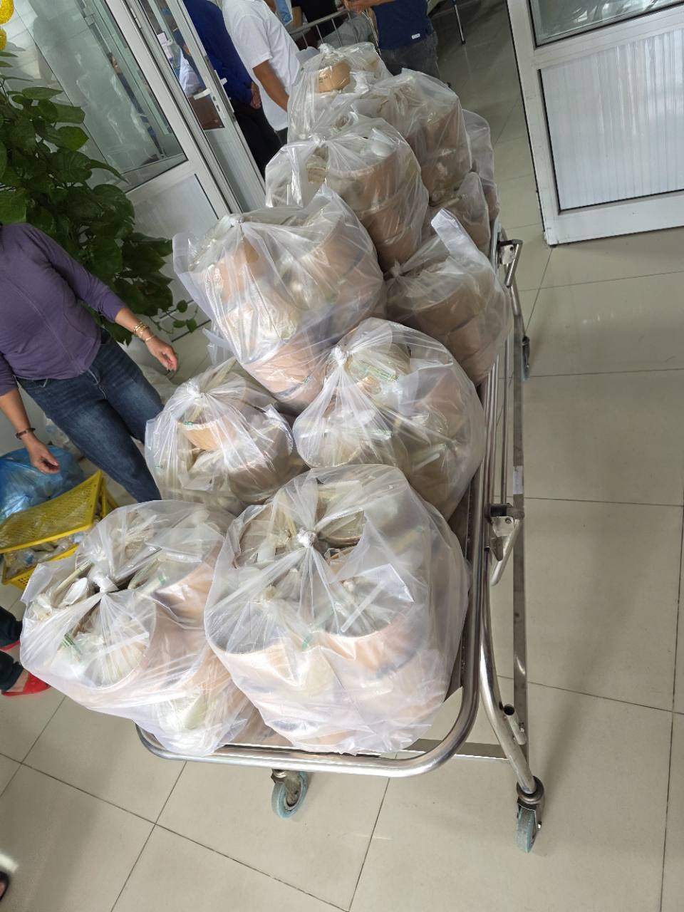A hospital trolley loaded with bagged meal sets.